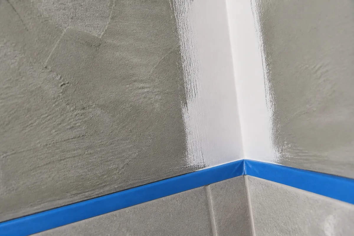 Détail d&rsquo;une sous-couche blanche appliquée à la brosse dans l&rsquo;angle d&rsquo;une paroi de salle d&rsquo;eau